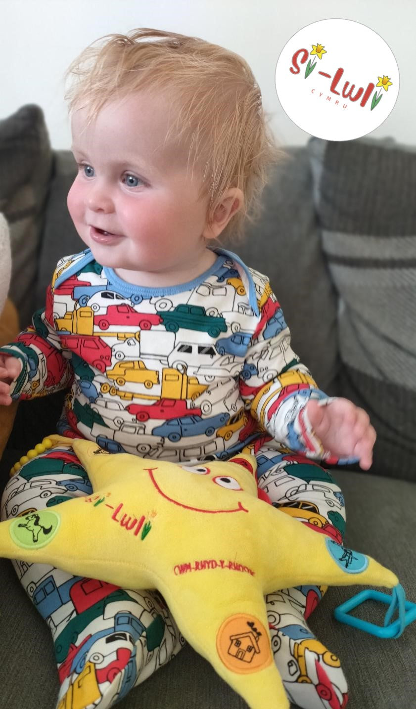 Baby boy playing with the Silwli Cymru Seren Swynol Welsh toy.